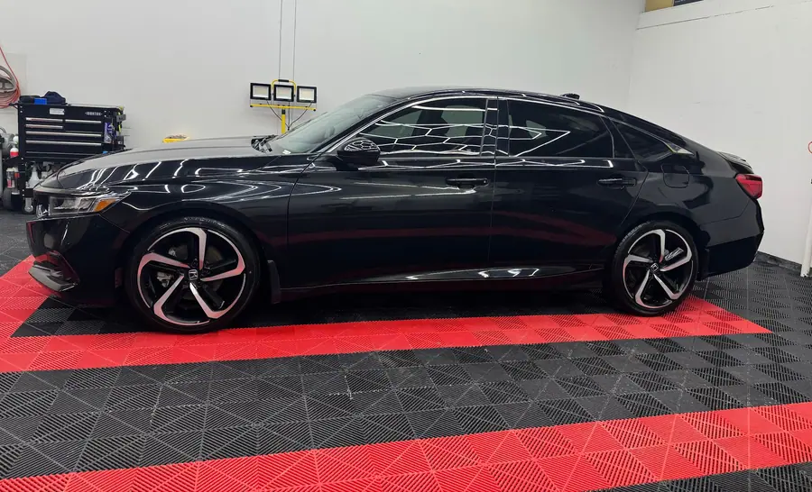 Black sedan with tinted windows in side profile on the shop floor