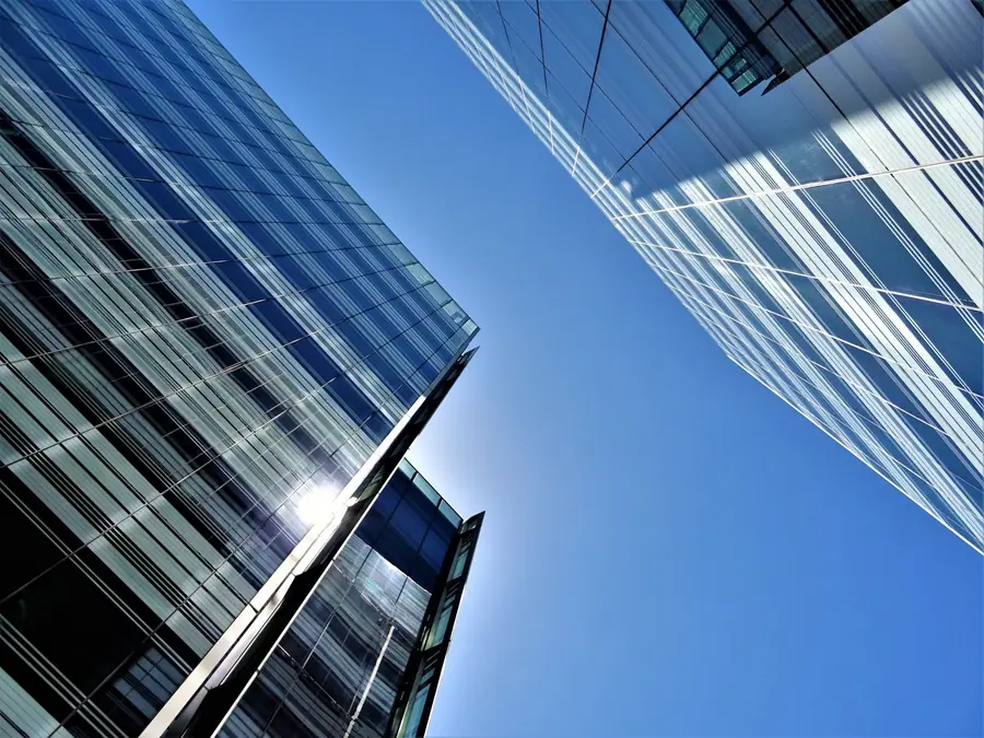 Looking up at blue glass office towers against the sky