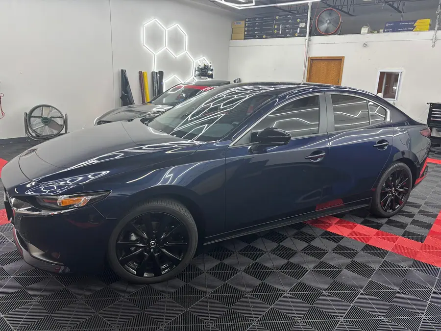 Navy sedan with every window tinted, parked under hexagon lights