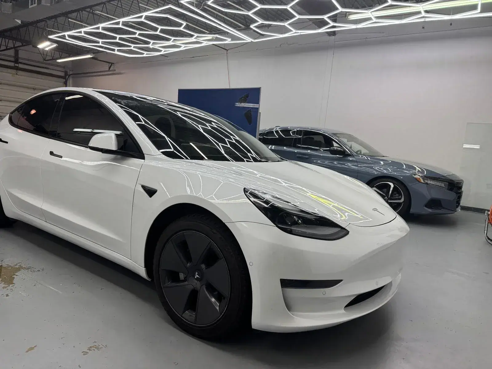 White Tesla Model 3 with tinted windows in the shop bay