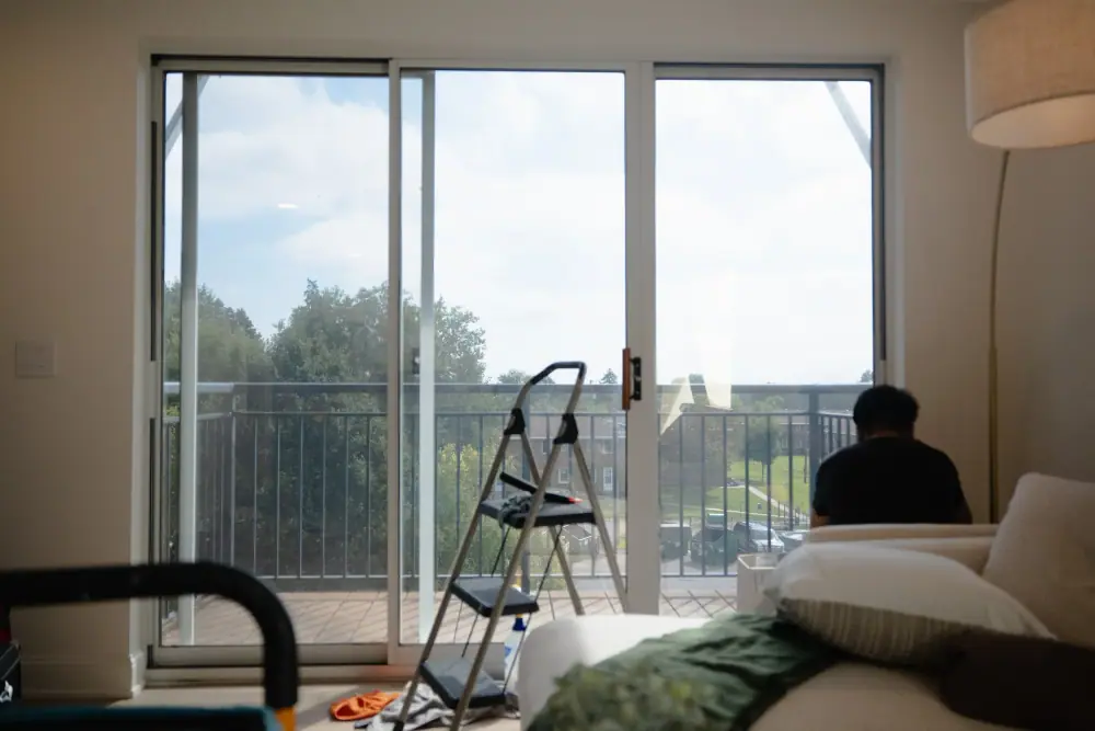 Installer working at a sliding glass door in a bright living room