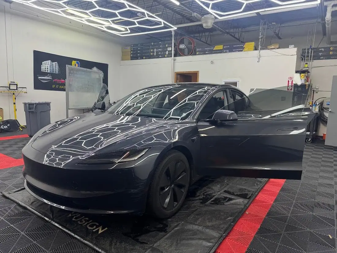 Tesla with freshly tinted glass, doors open, hexagon lights reflecting across the hood